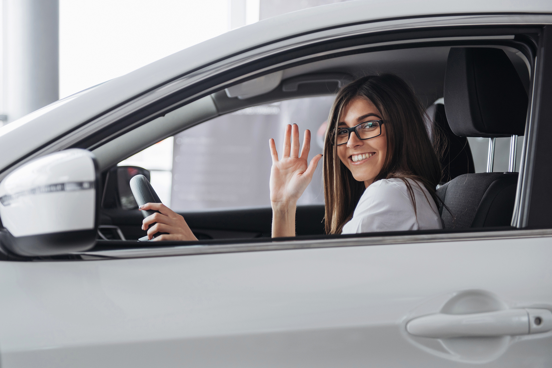Pretty young woman driving new car. Mujer-con -licencia-de-conducir